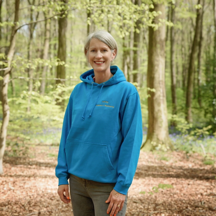 Natalie stood in woods wearing branded hoodie