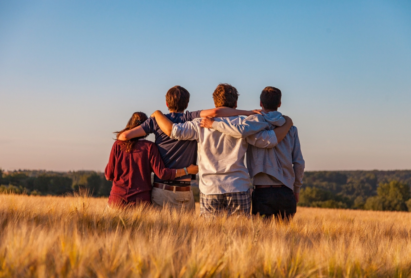 Group of friends stood arm in arm in a field